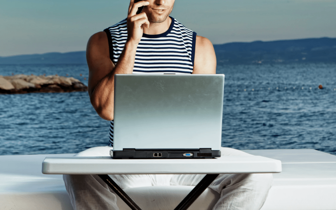 man working on laptop with ocean in the background